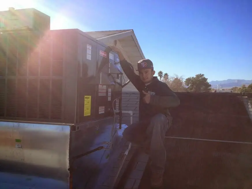 HVAC technician performing AC Tune-Up on a rooftop unit in Helena